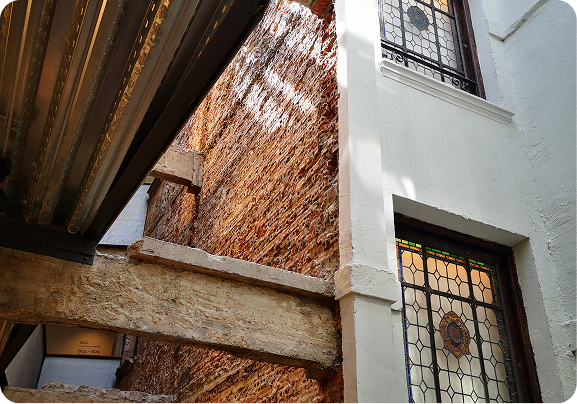 Inner courtyard at Tayko Bilbao, featuring an original brick wall, wooden beams and stained-glass windows
